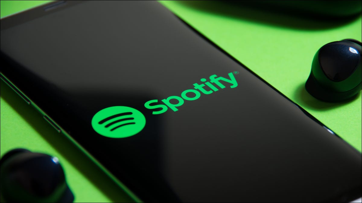 Logotipo de Spotify en un teléfono inteligente junto a auriculares verdaderamente inalámbricos